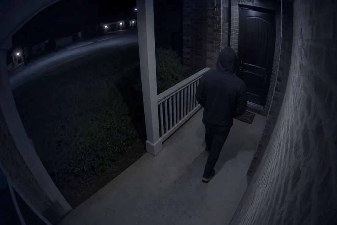 Night view of an unknown person approaching a dark front porch